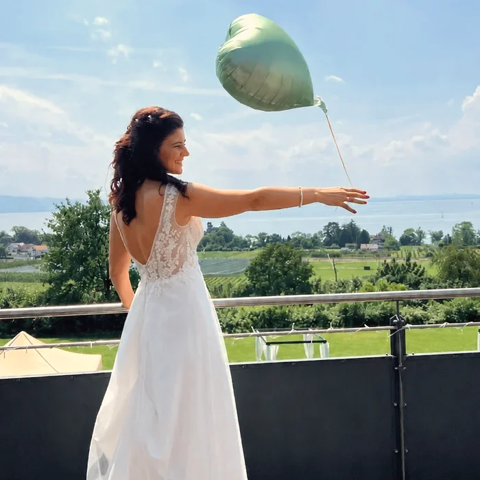 Braut mit Herzballon auf einer Terrasse am See